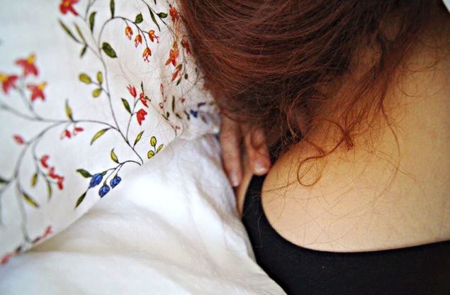 Rear view of woman sleeping on bed at home