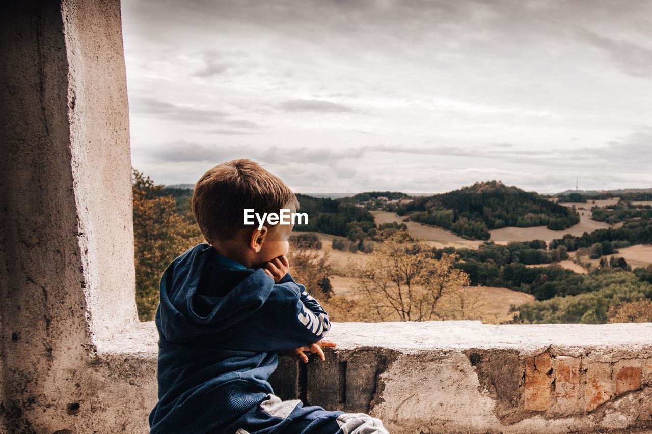 Side view of boy looking at landscape against sky