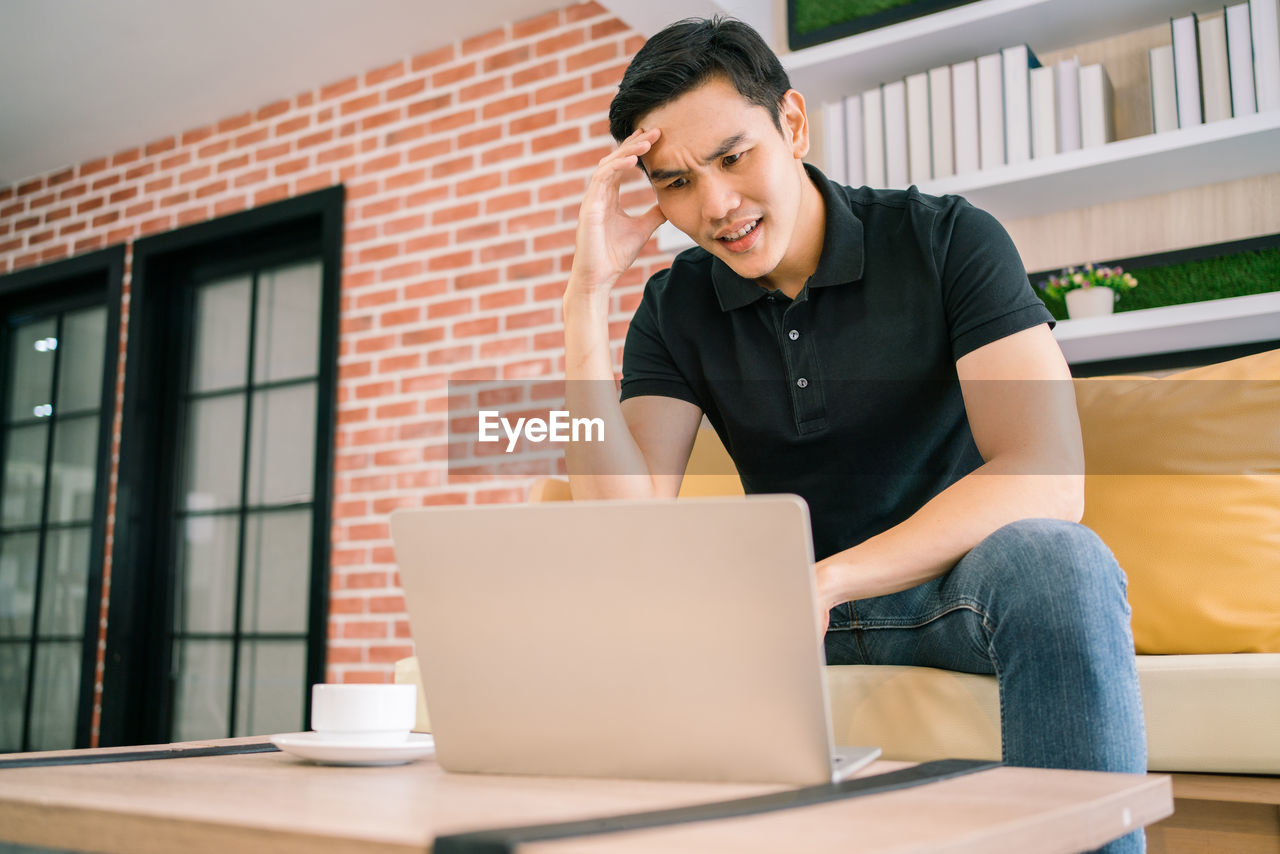 Depressed businessman using laptop at office