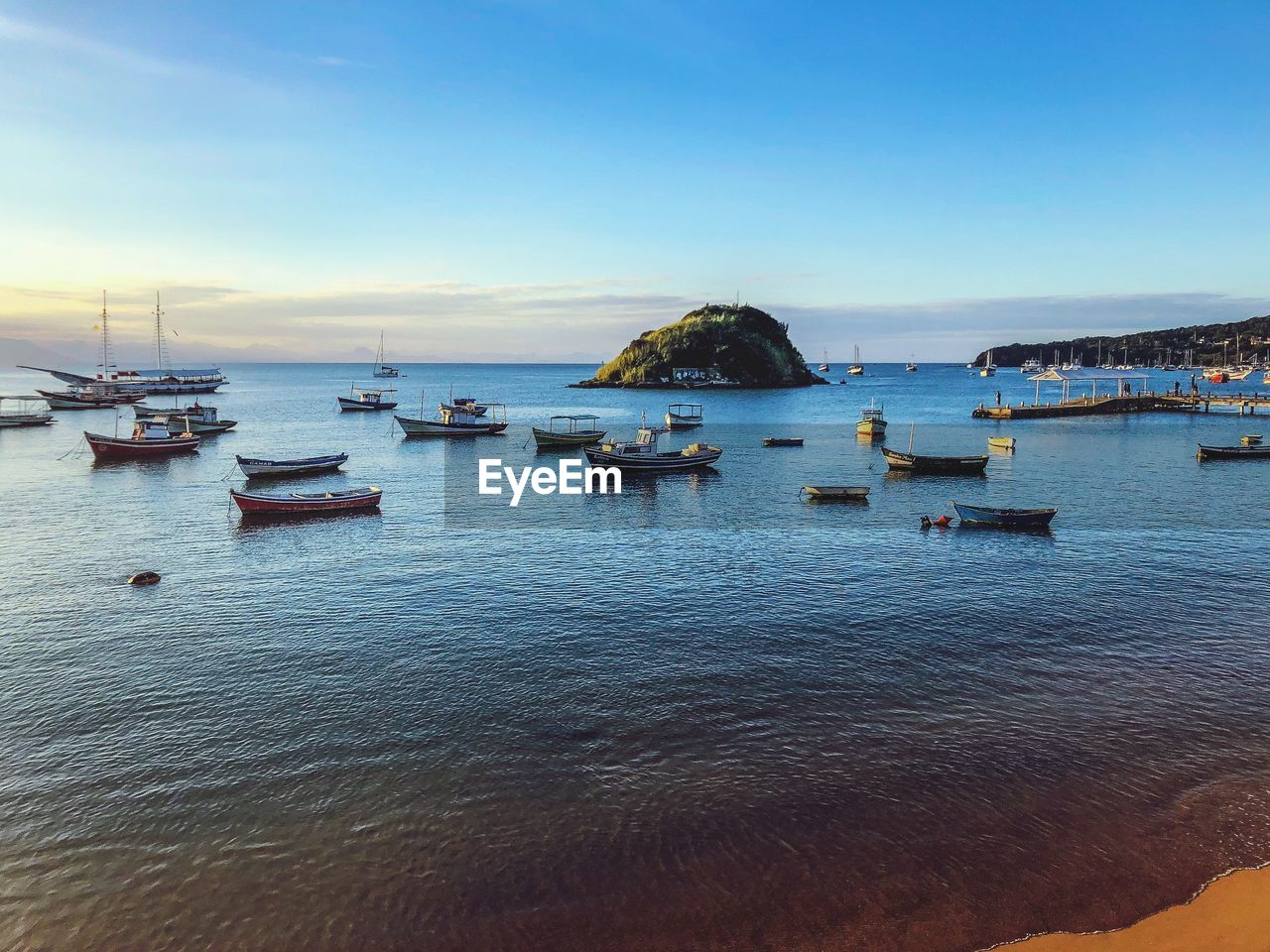 Boats moored in sea at sunset