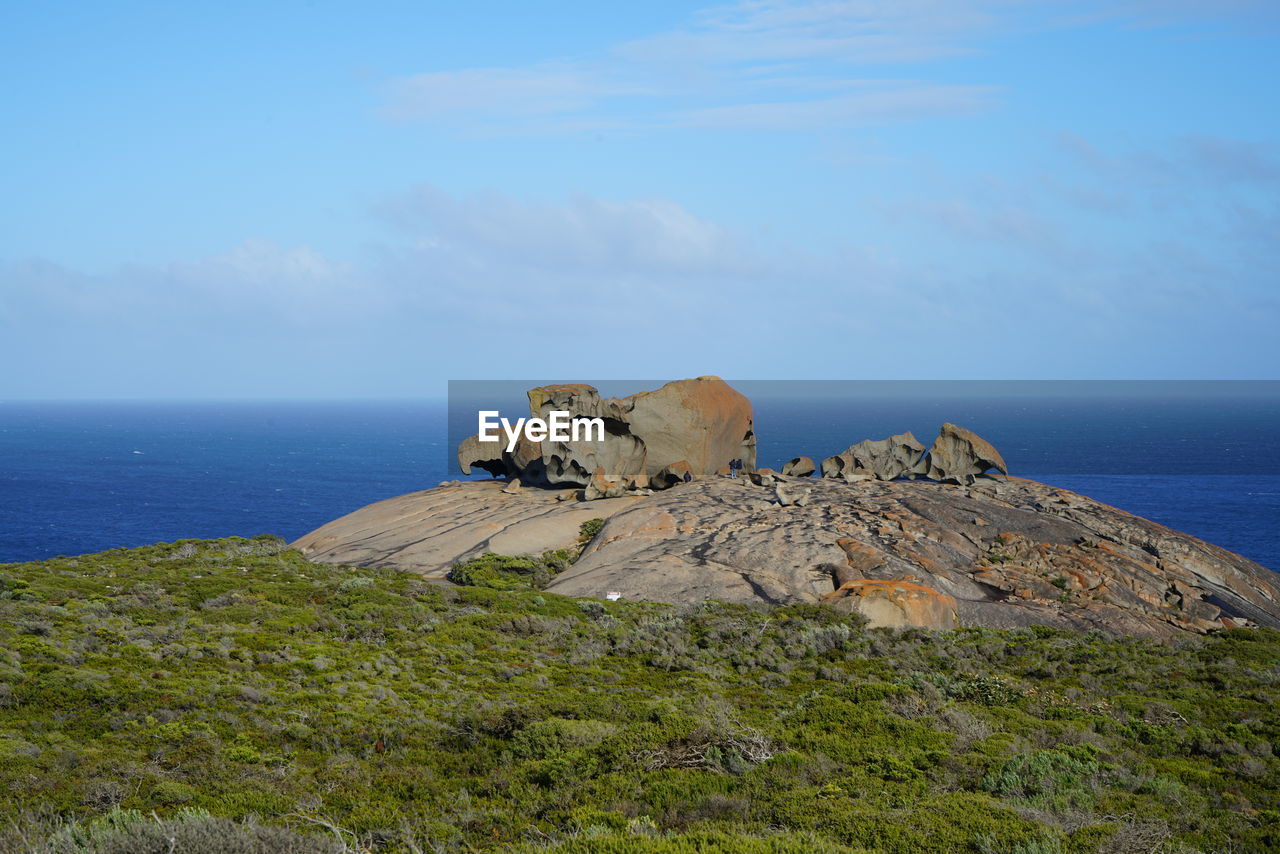 Scenic view of rocks by sea against sky