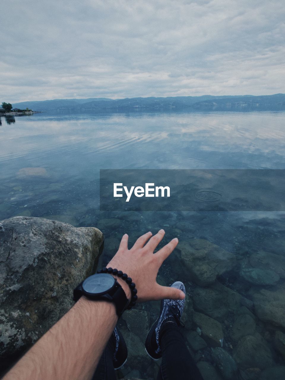 Close-up of hand reaching for lake