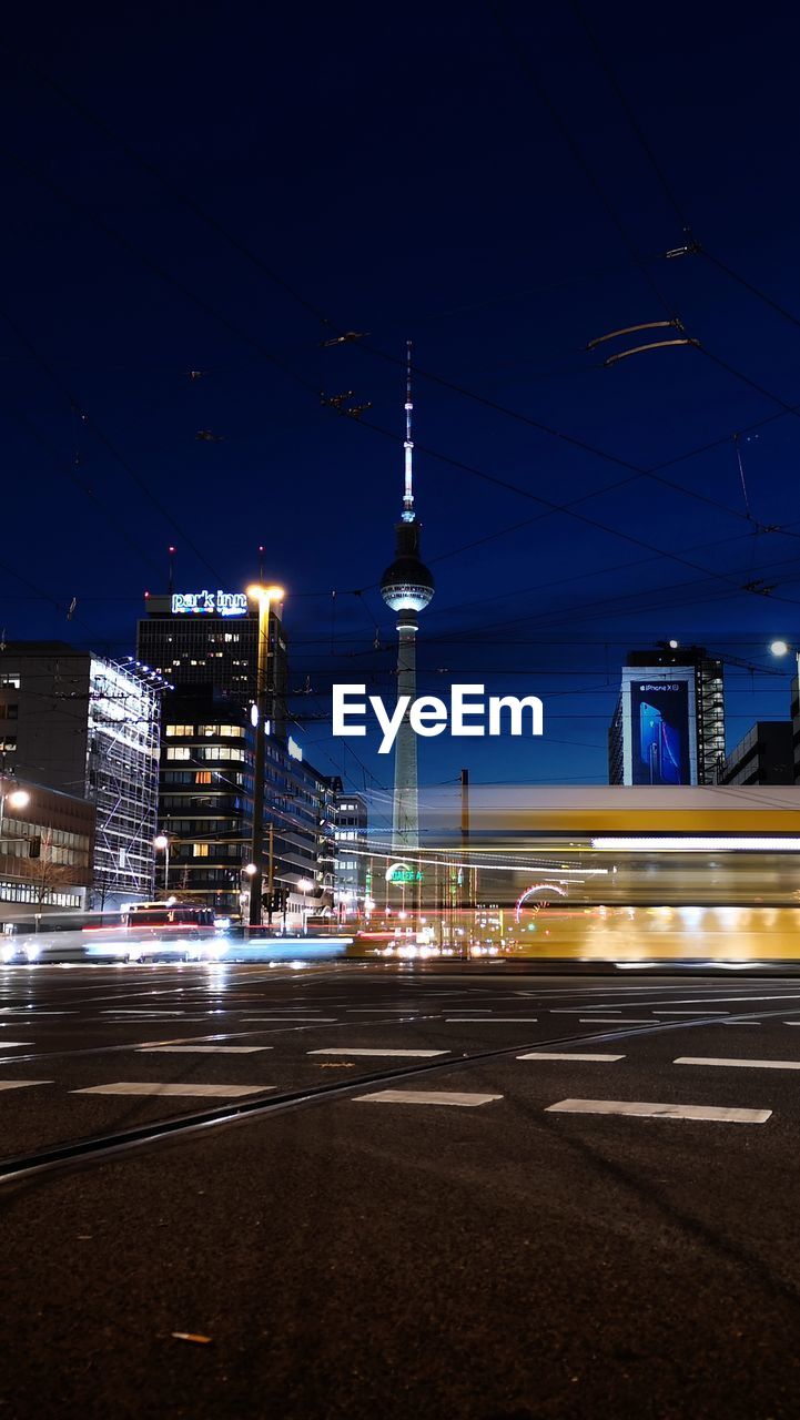 LIGHT TRAILS ON CITY STREET AGAINST SKY AT NIGHT
