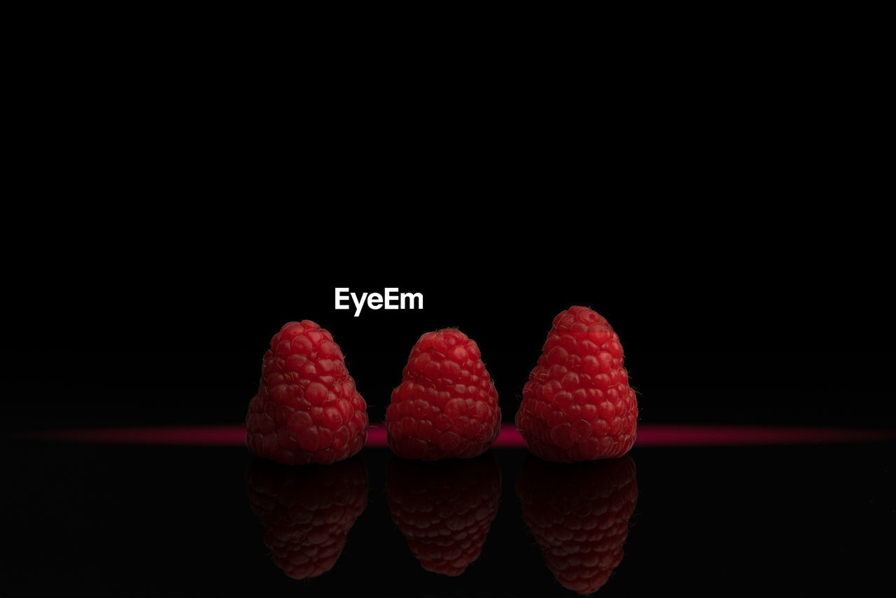 Red raspberries on black background