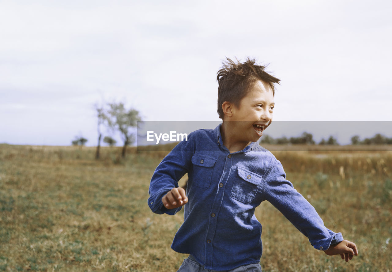 Boy with down syndrome running while looking back over shoulder