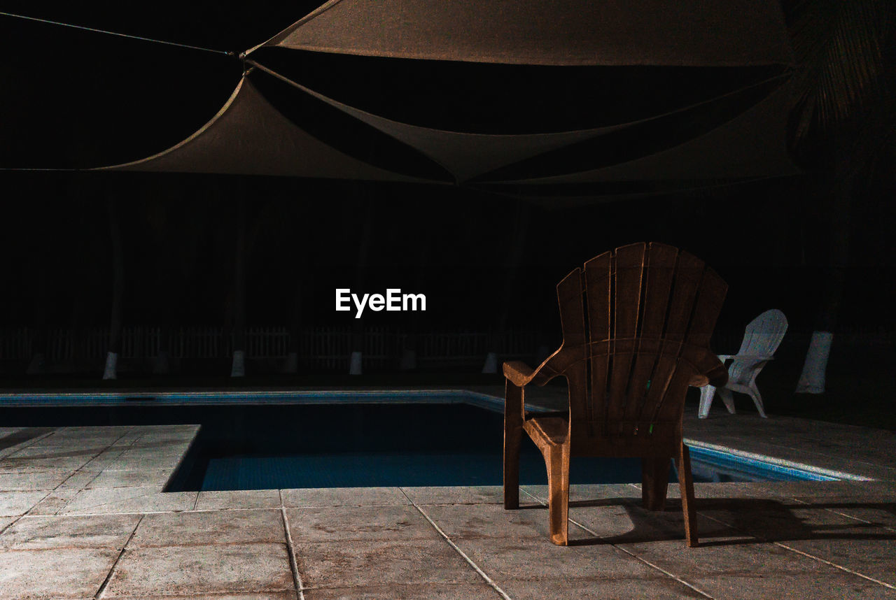 Empty chairs by the pool