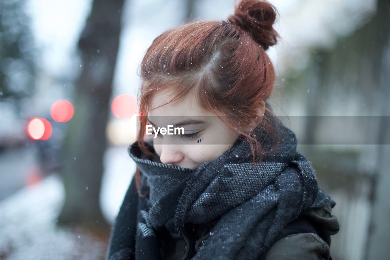 Close-up of smiling young woman during snowfall