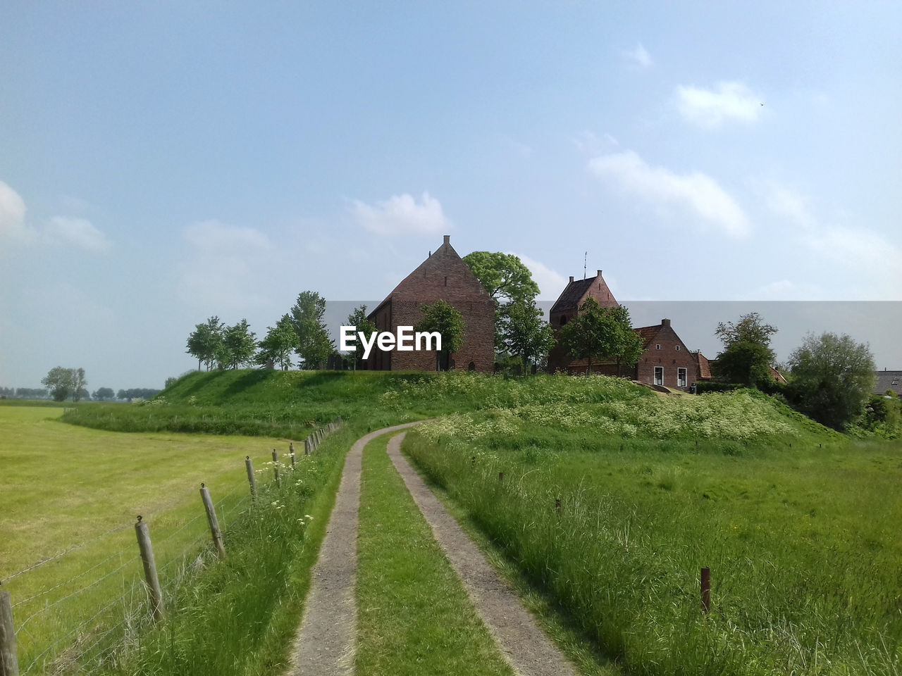 Scenic view of field by houses against sky