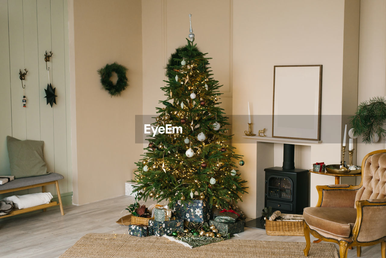 Scandinavian beige christmas interior with decorated christmas tree. fireplace with armchair, wreath