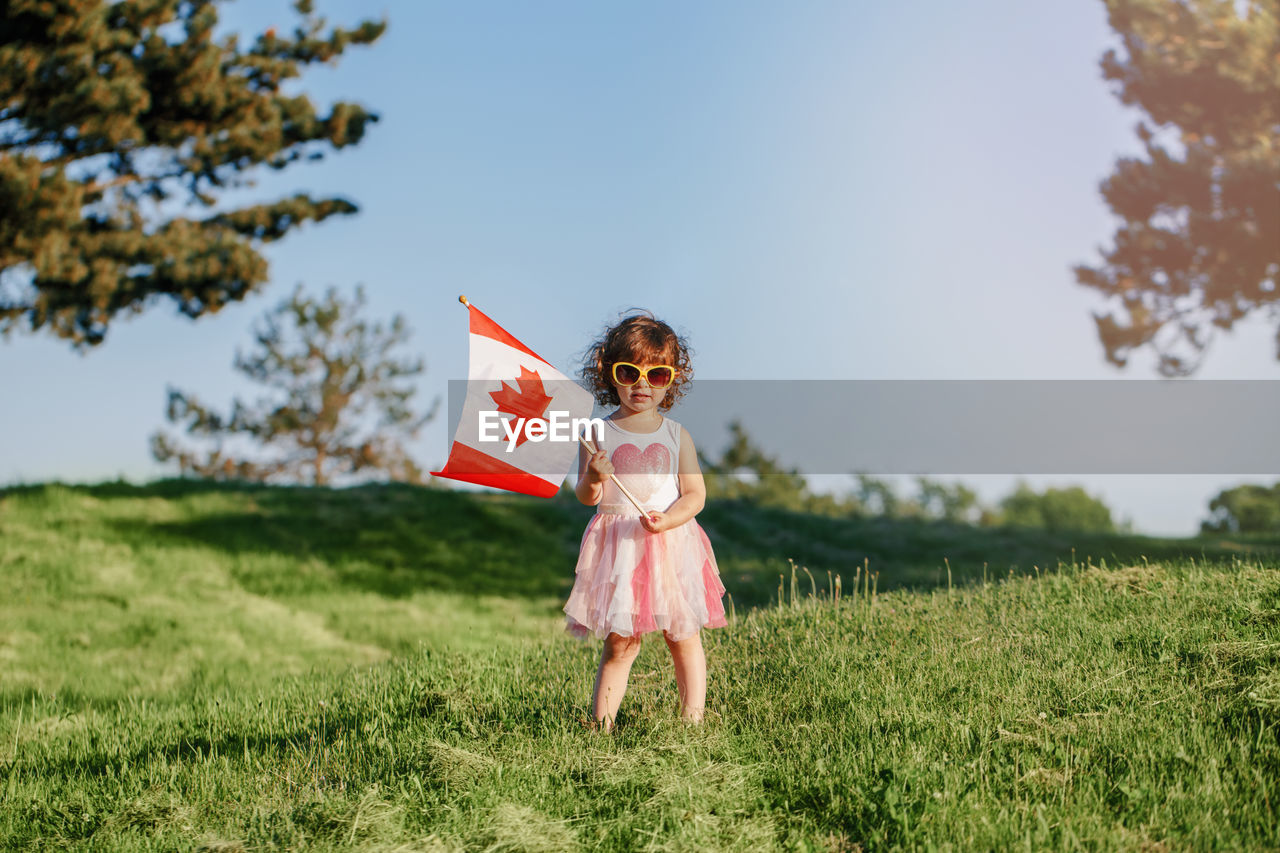 Girl holding canadian flag standing on land