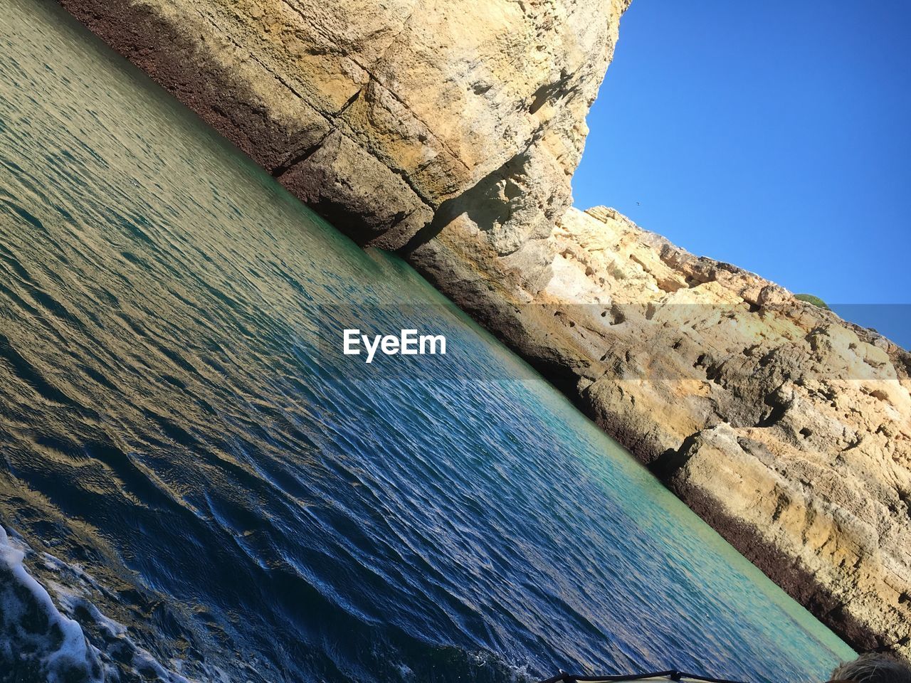 LOW ANGLE VIEW OF ROCK FORMATION AGAINST CLEAR BLUE SKY