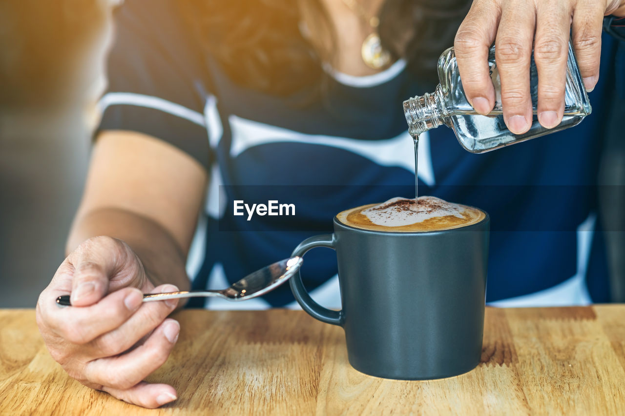 midsection of woman holding coffee at table