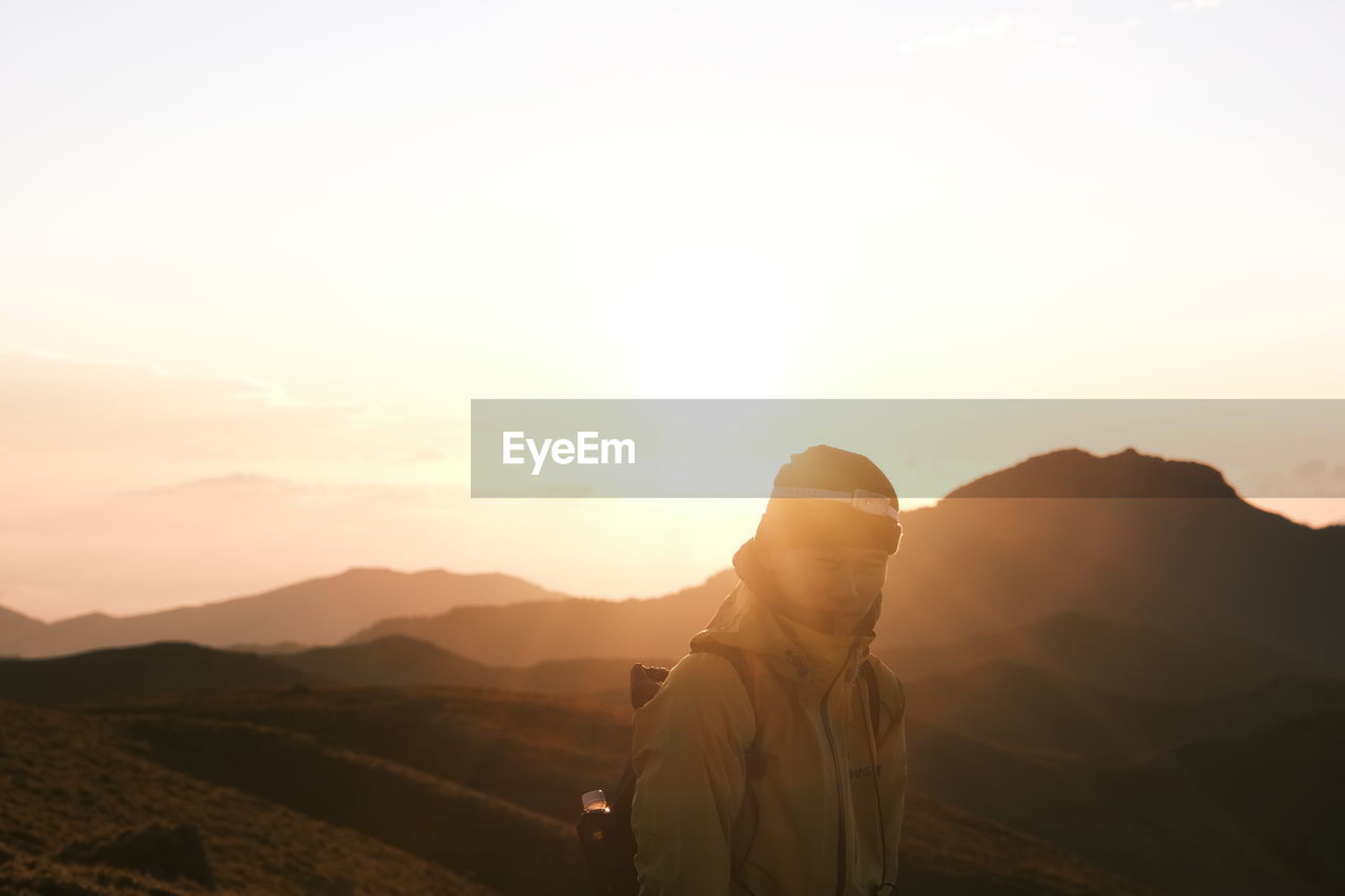 Man standing on mountain against sky during sunset