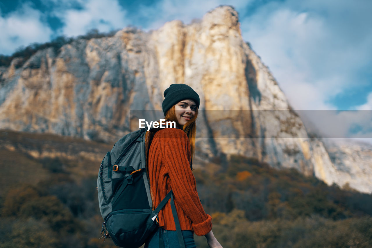 WOMAN STANDING ON ROCK AGAINST MOUNTAIN