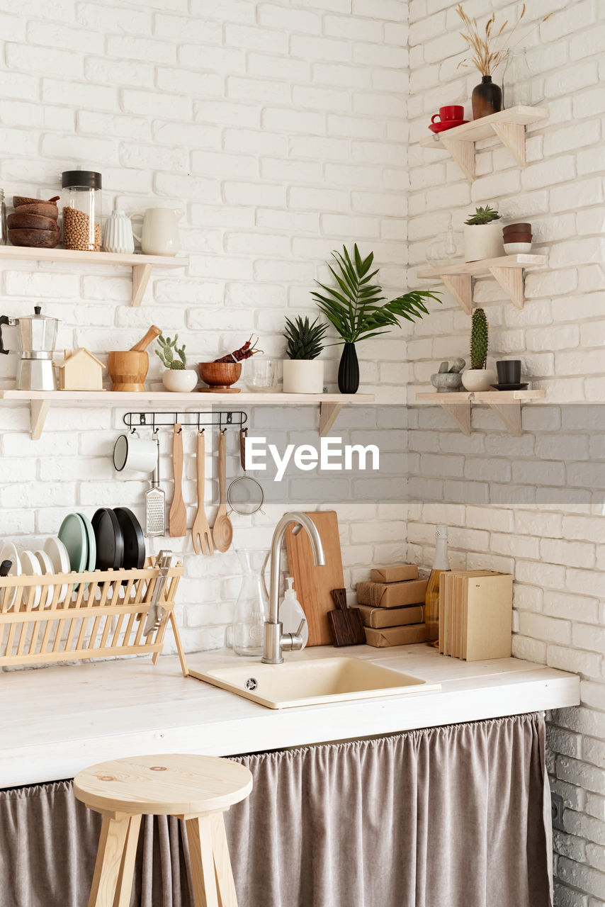 Rustic kitchen interior with brick wall and white wooden shelves