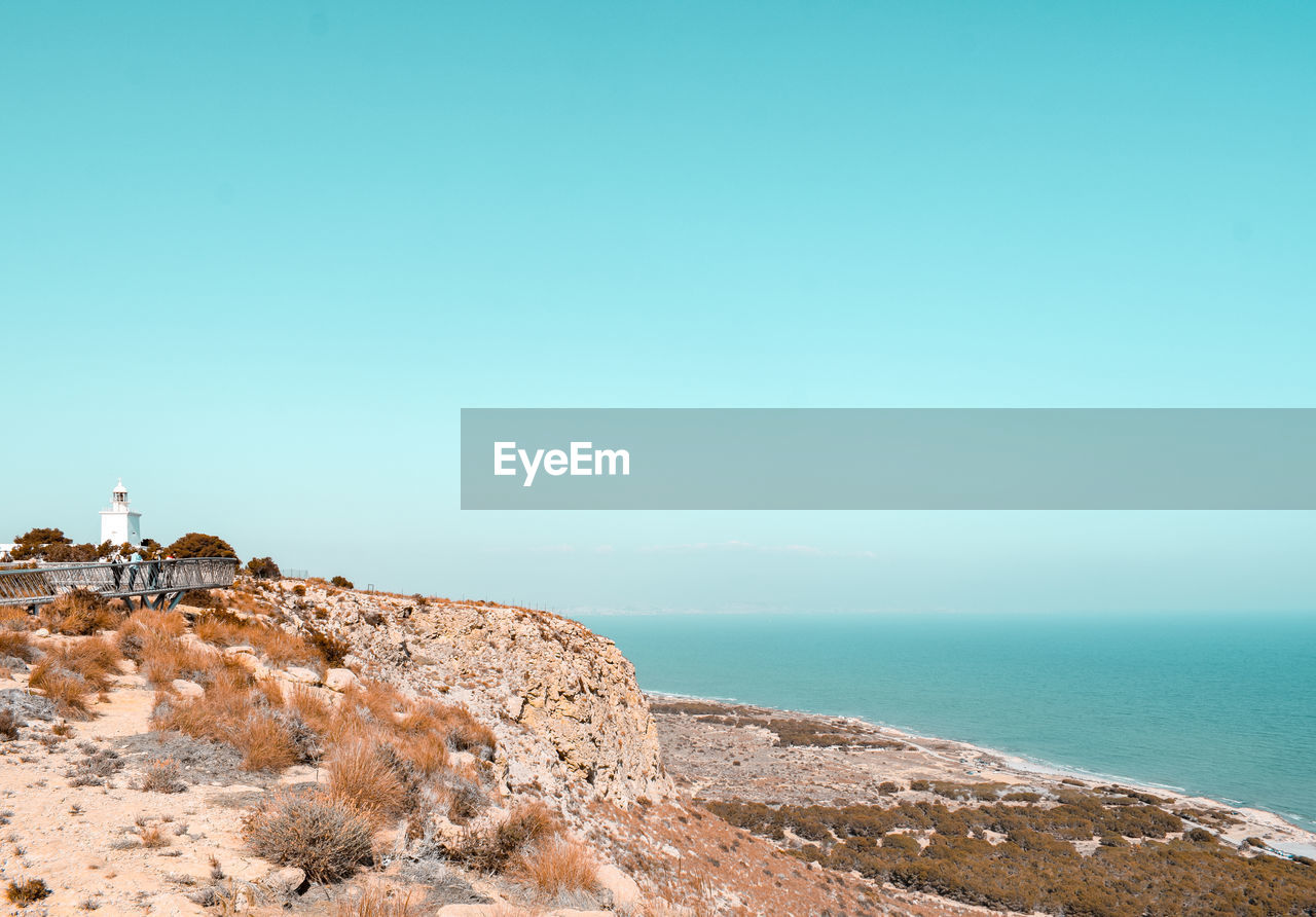 Scenic view of sea against clear sky with lighthouse on cliff