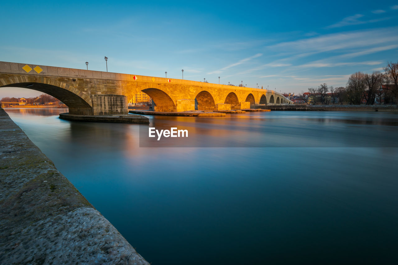 Arch bridge over river against sky