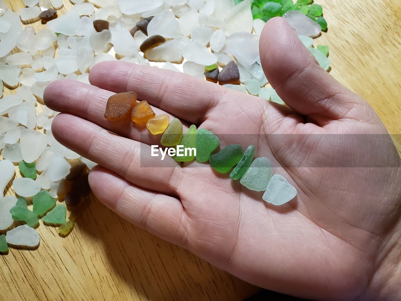 Cropped hand holding stones on table