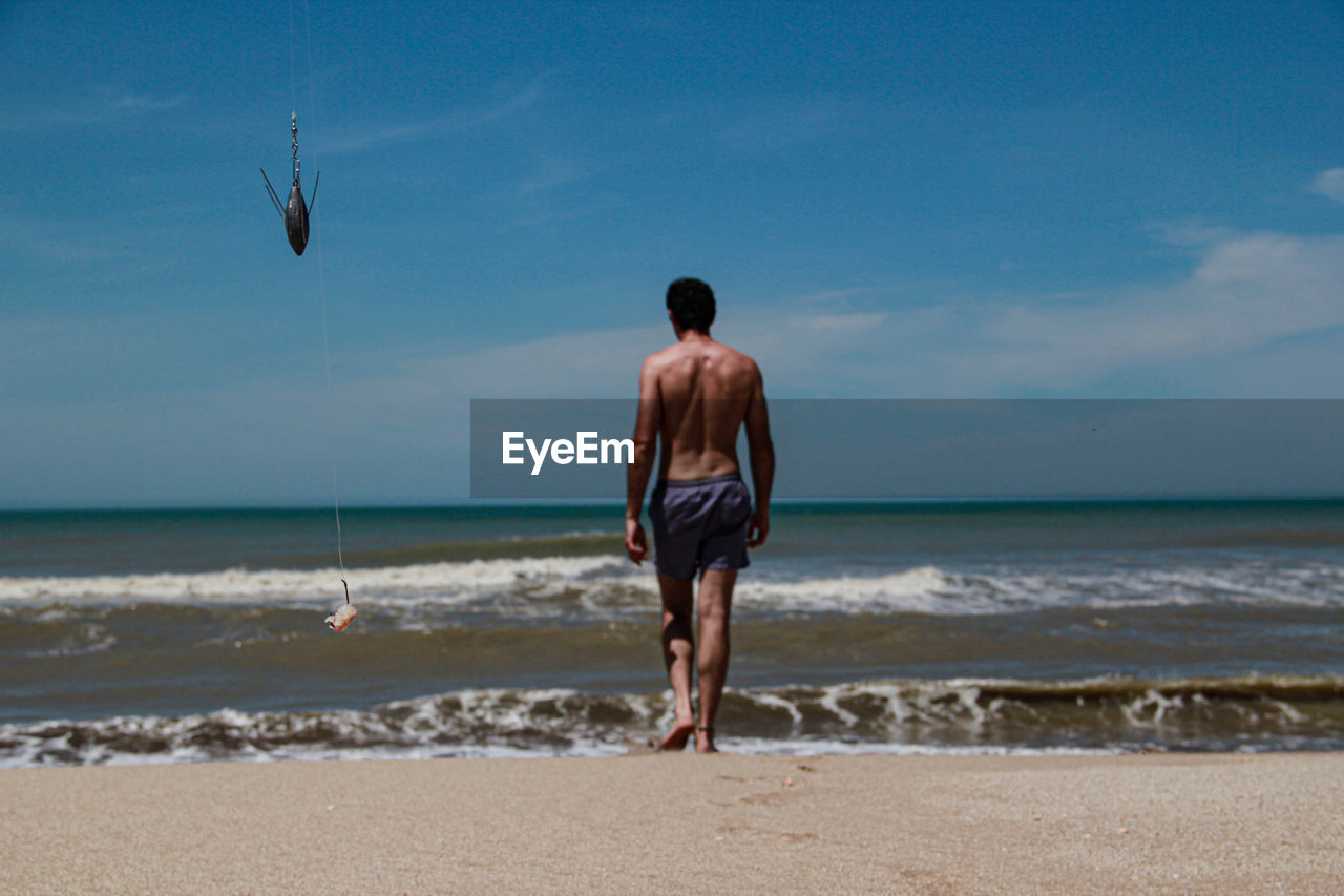 REAR VIEW OF MAN ON BEACH