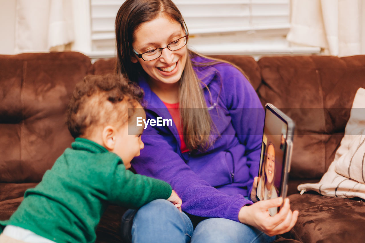 Smiling mother and son talking on video call at home