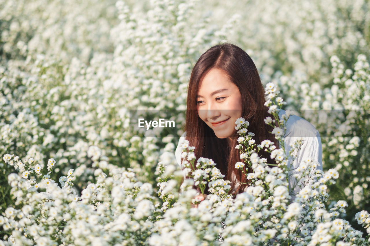 Beautiful woman looking ay white flowers