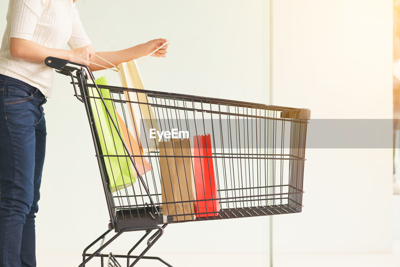 Midsection of woman with shopping cart in store