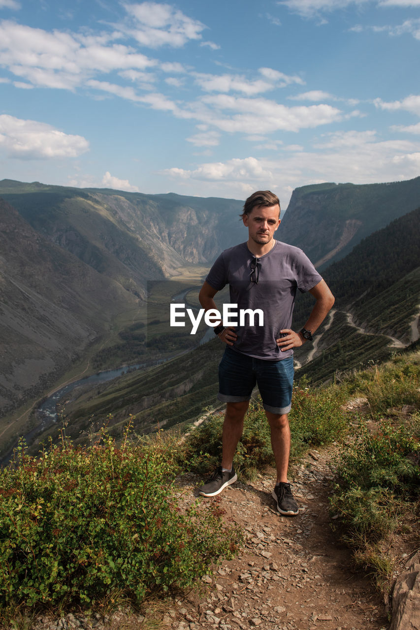 FULL LENGTH OF YOUNG MAN STANDING ON MOUNTAIN