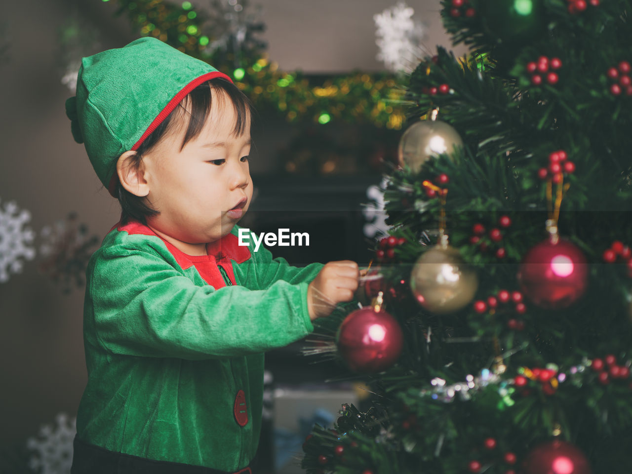 Cute baby girl by christmas tree at home