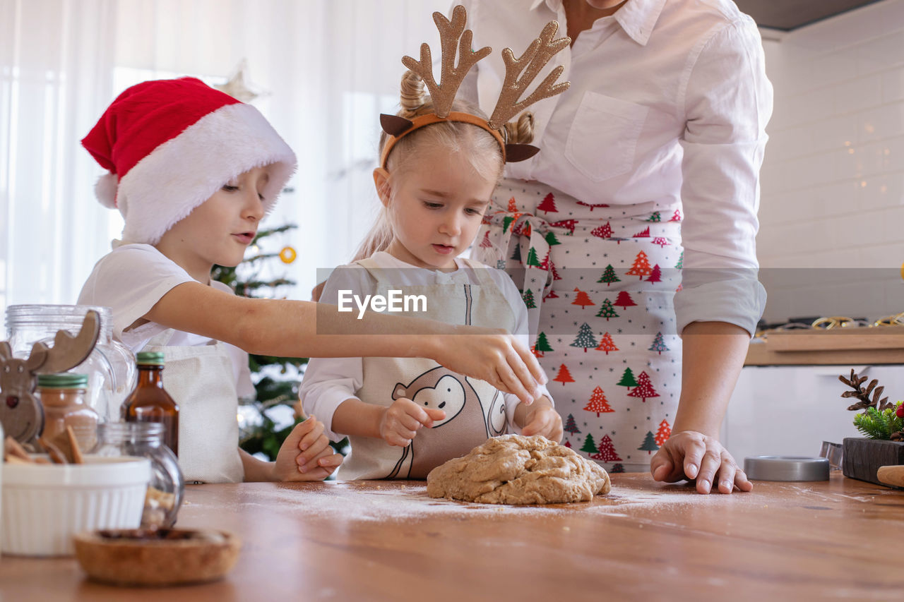 Midsection of mother and kids preparing food at home