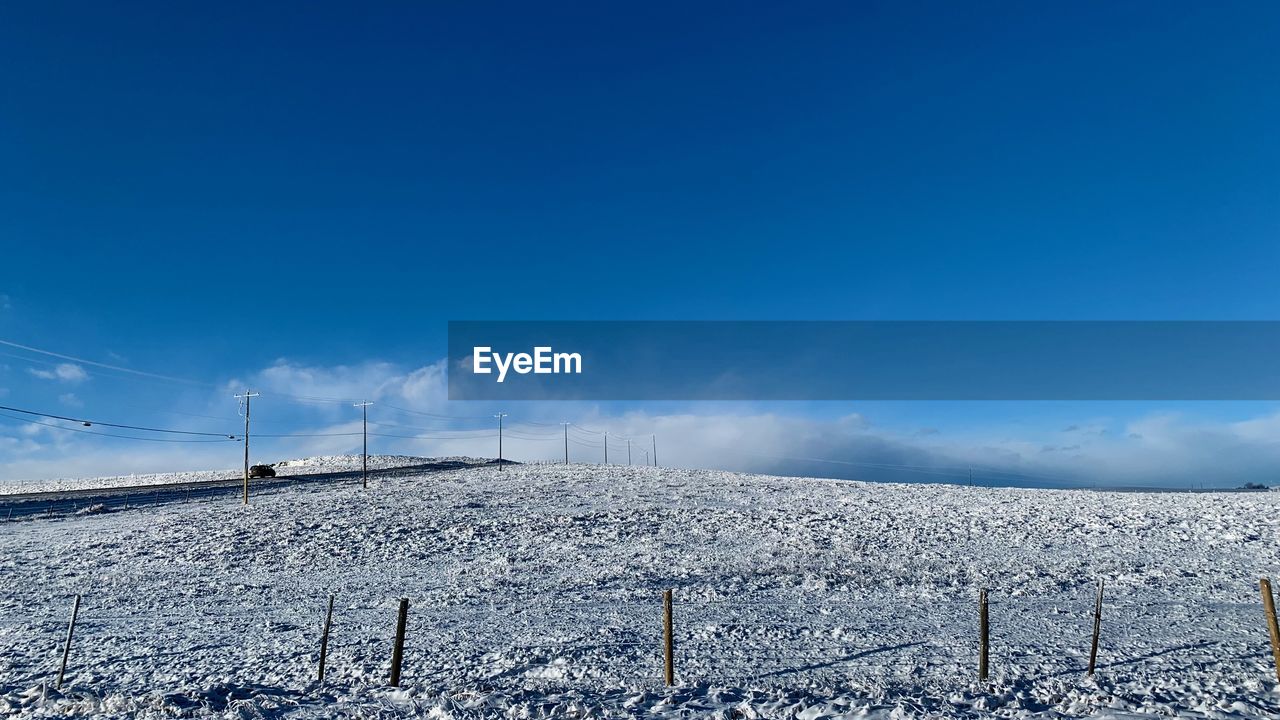 SNOW COVERED LAND AGAINST BLUE SKY