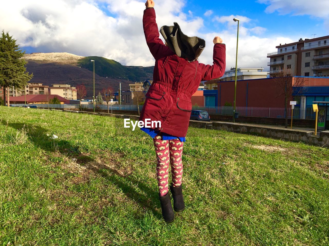 Rear view full length of girl standing on field against sky