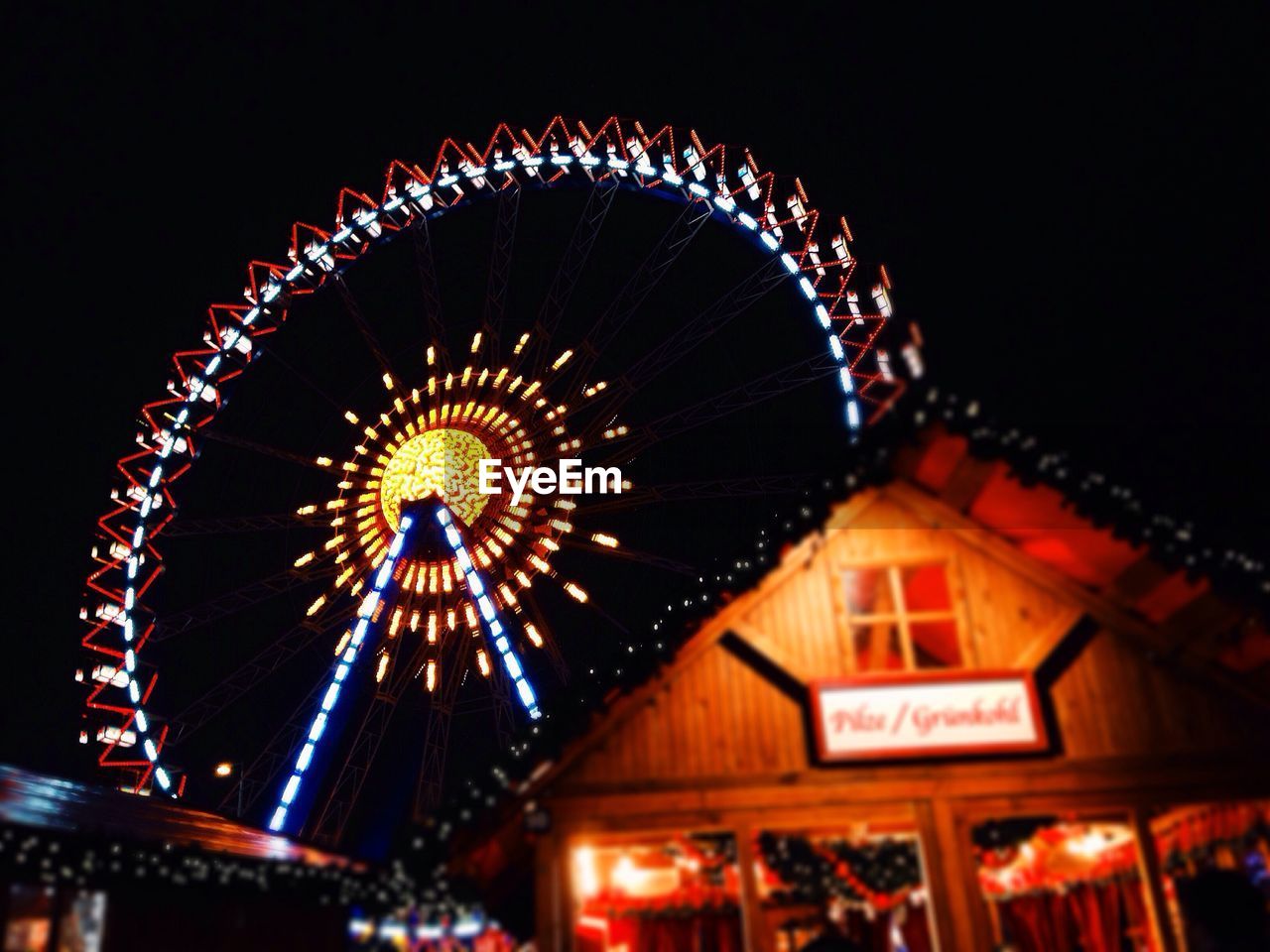 LOW ANGLE VIEW OF ILLUMINATED FERRIS WHEEL AT NIGHT