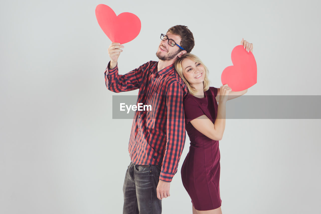 YOUNG COUPLE HOLDING HEART SHAPE ON WHITE