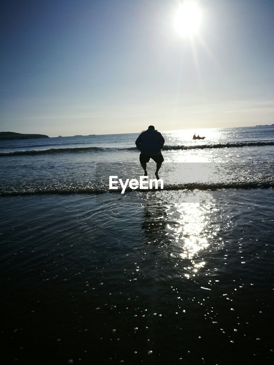 SILHOUETTE MAN WALKING ON BEACH AGAINST SUNSET SKY