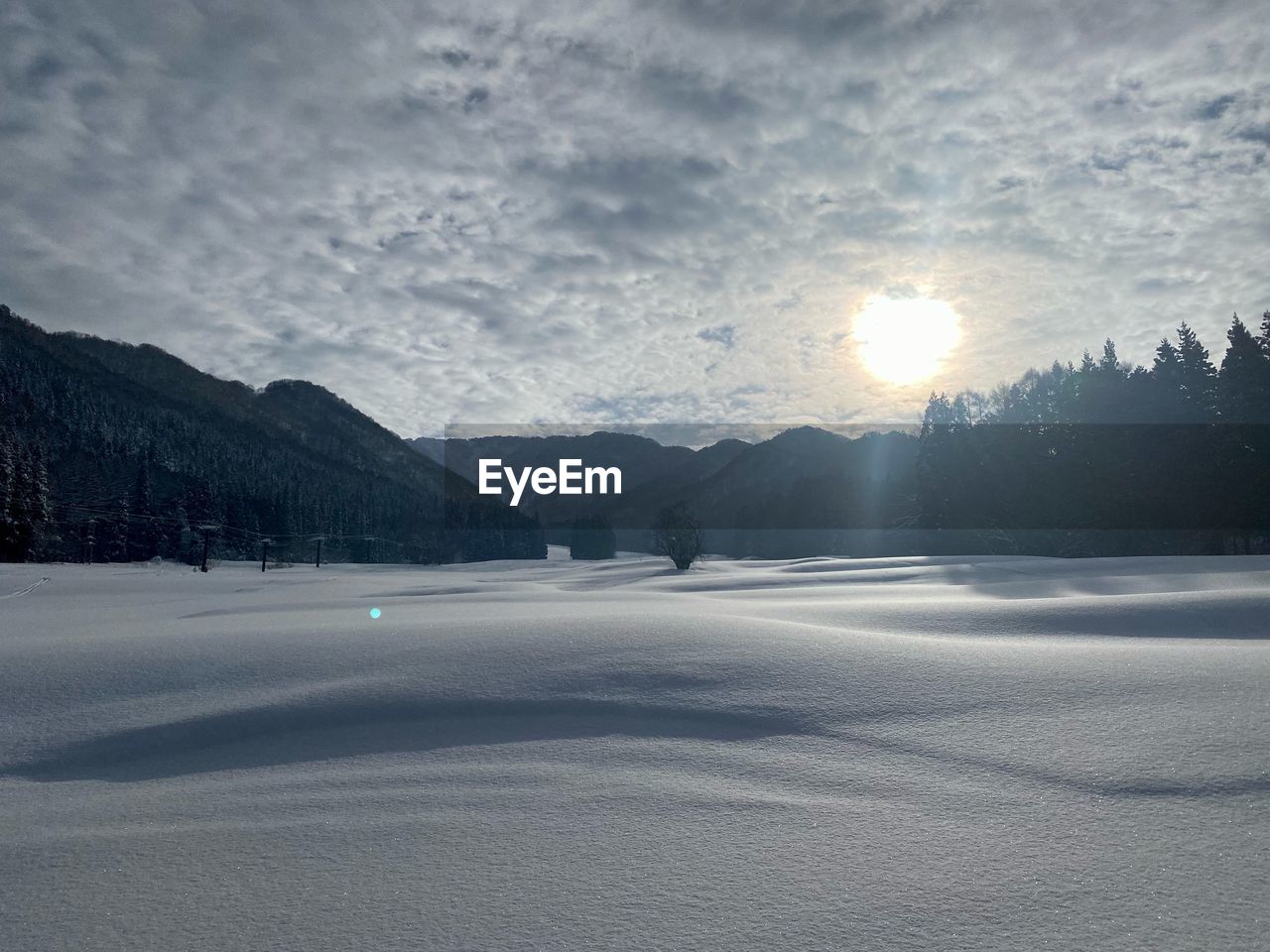 sky, mountain, scenics - nature, snow, winter, cold temperature, environment, beauty in nature, landscape, nature, cloud, tranquility, tranquil scene, mountain range, no people, tree, land, sunlight, non-urban scene, morning, frozen, sun, ice, travel, water, horizon, plant, lake, outdoors, travel destinations, freezing, idyllic, coniferous tree, sunbeam, pinaceae, day, forest, dawn, remote