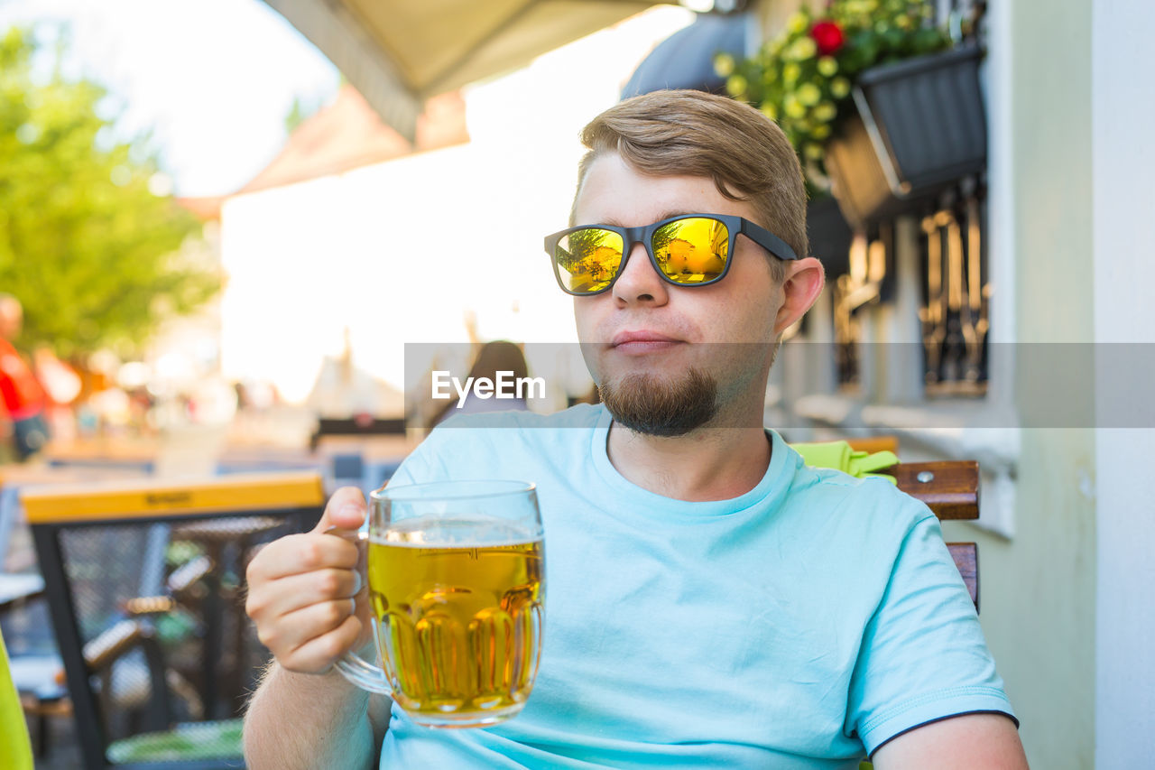 PORTRAIT OF YOUNG MAN DRINKING GLASS IN A BEER
