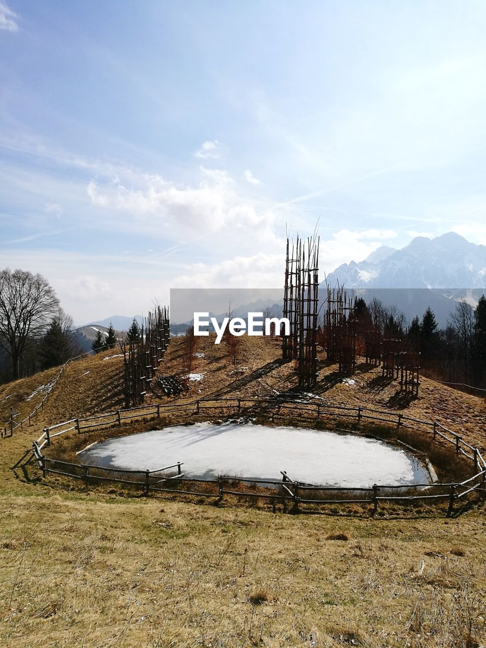 Mountain field with lake against sky