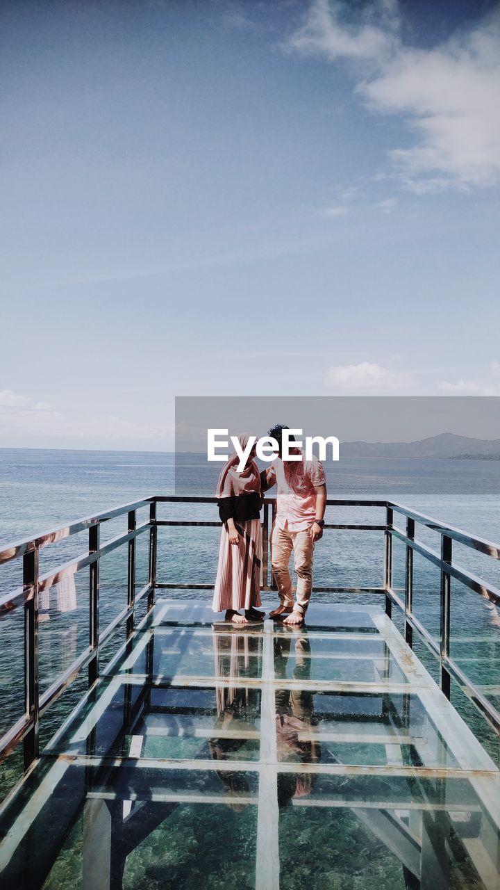 People at observation point by sea against sky