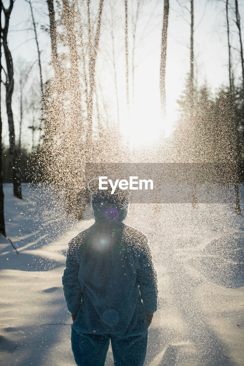 REAR VIEW OF MAN STANDING ON SNOW COVERED LANDSCAPE