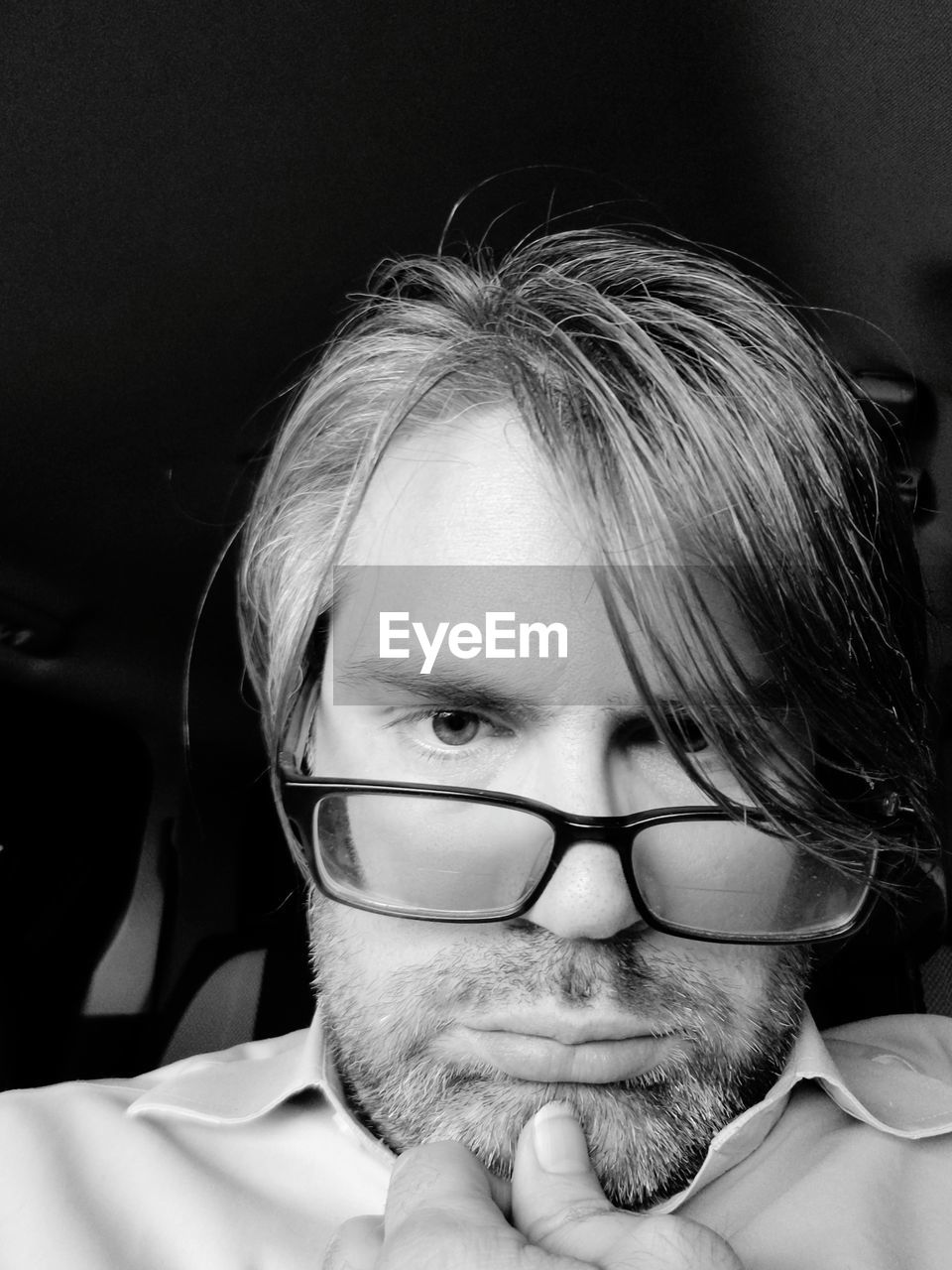 Low angle portrait of mid adult man wearing eyeglasses in darkroom