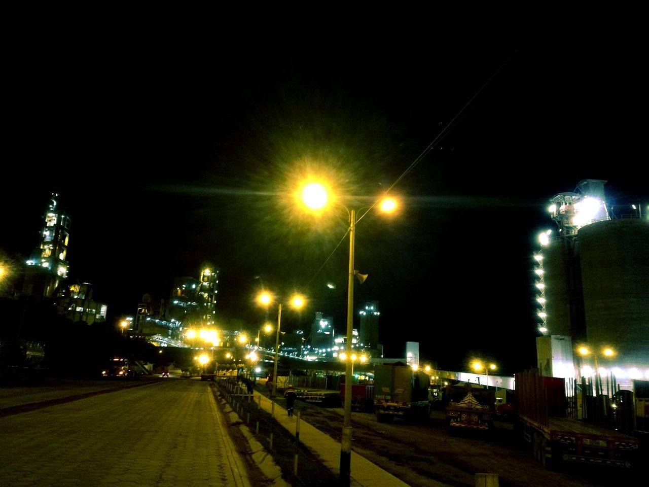 ILLUMINATED TRAIN ON RAILROAD TRACKS AGAINST SKY AT NIGHT