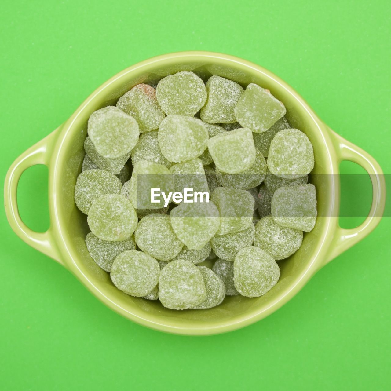 Directly above view of candies in bowl on green background