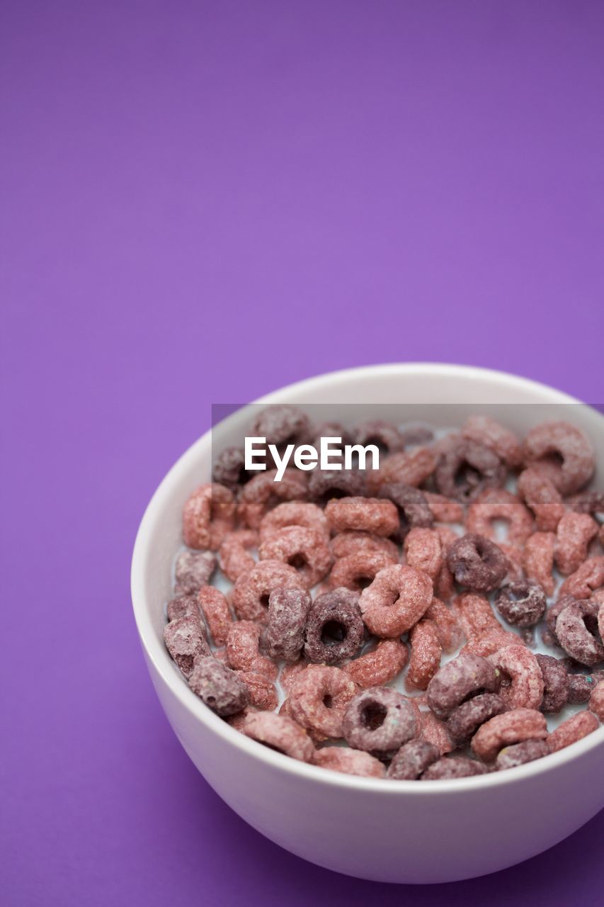 High angle view of breakfast cereal in bowl against purple background