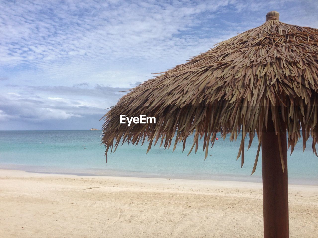 View of beach umbrella on beach against cloudy sky