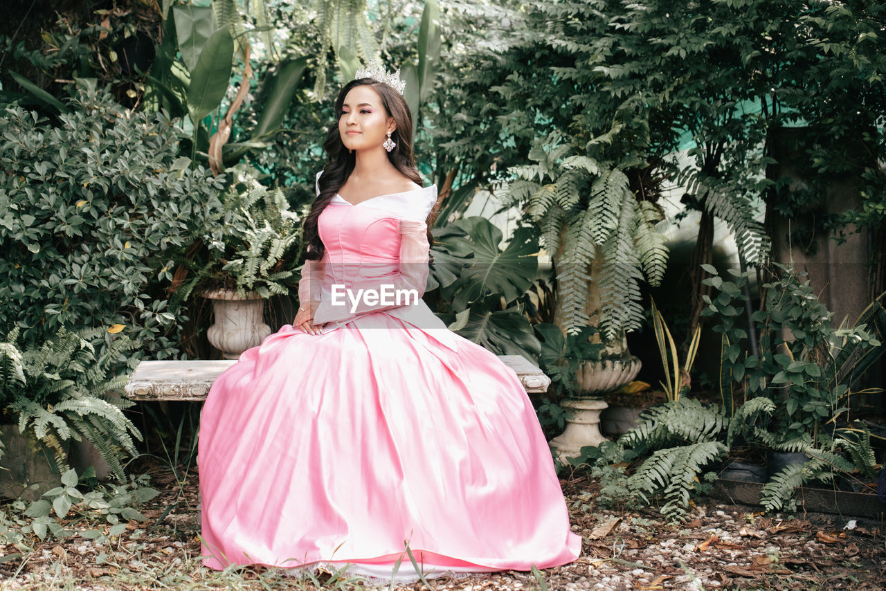 Full length of woman sitting against plants outdoors