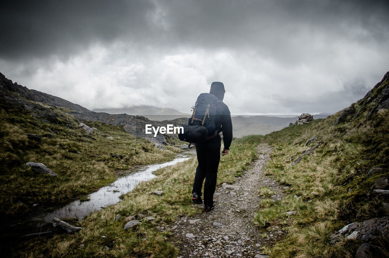 Rear view of woman walking on mountain against sky