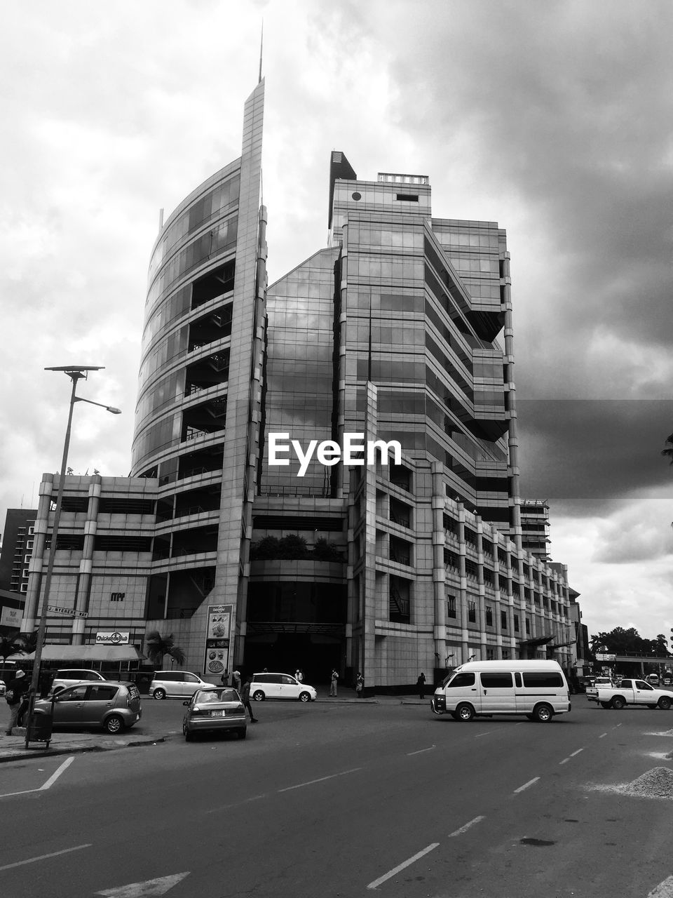 VEHICLES ON ROAD BY BUILDINGS AGAINST SKY