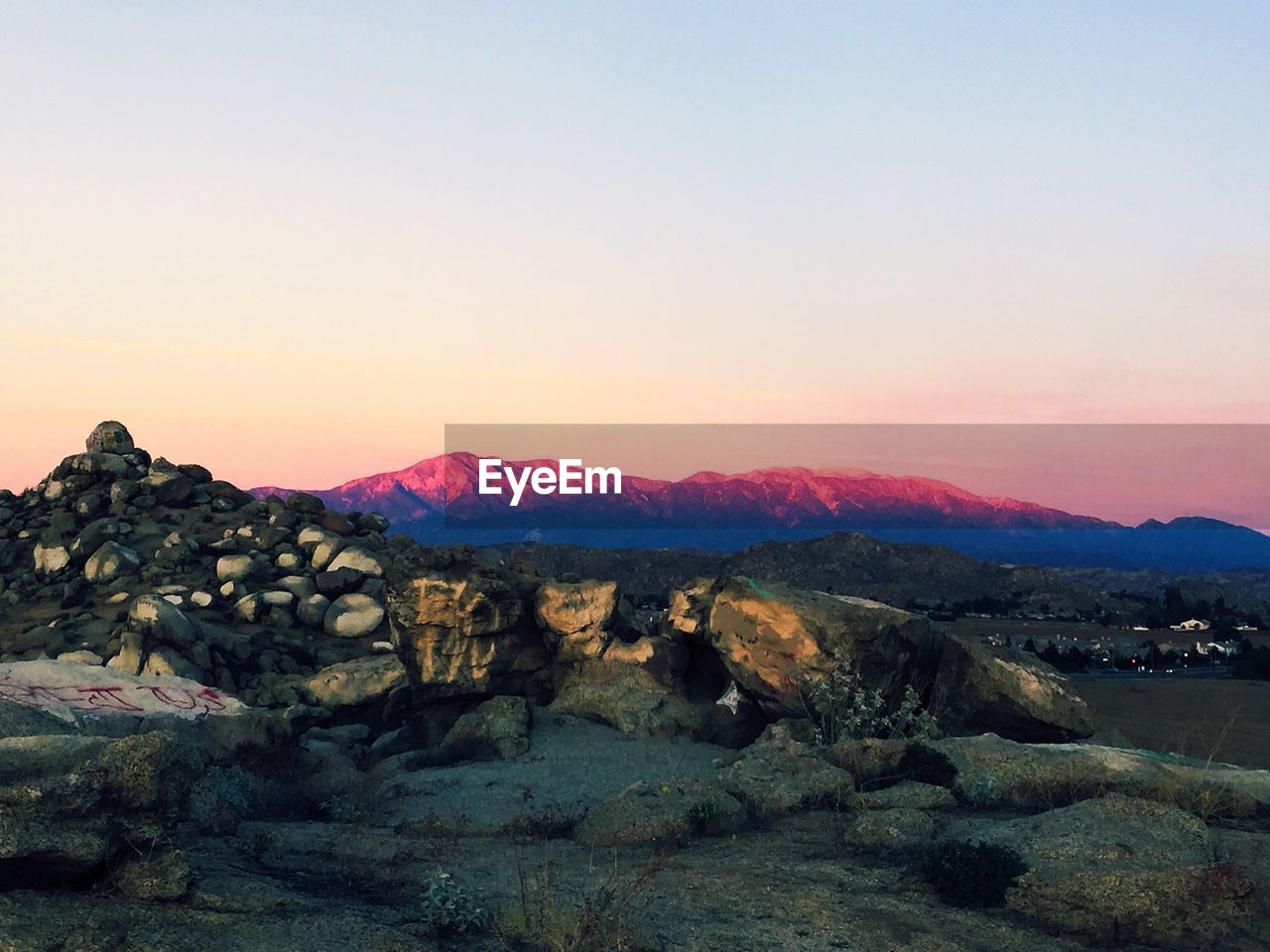 Boulders on mountain against sky at sunset