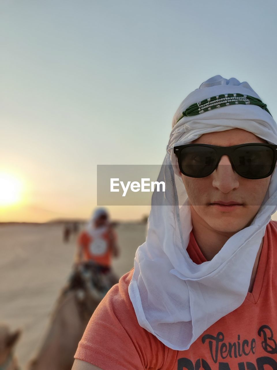 Portrait of man in sunglasses wearing headscarf against sky during sunset