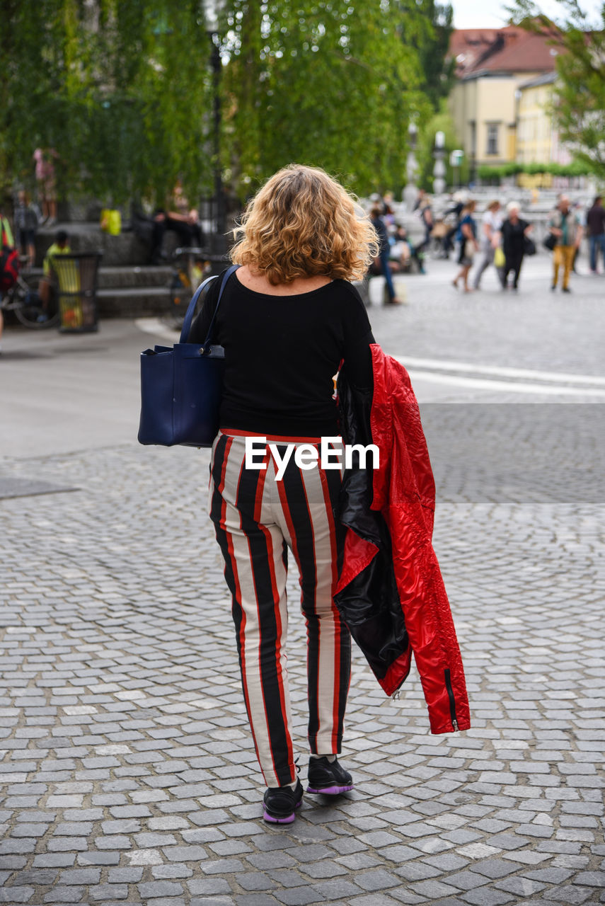 Rear view of woman standing on footpath in city